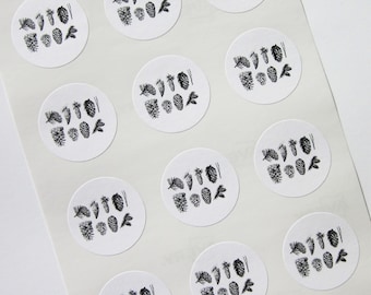 Könnte beinhalten: Ein Blatt weißes Papier mit 10 runden Aufklebern mit Schwarzweiß-Illustrationen von Tannenzapfen. Jeder Aufkleber hat eine andere Anordnung von Tannenzapfen.