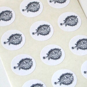 May include: A sheet of white paper with 12 black and white stickers featuring a cartoon pufferfish. Each sticker is round and has a white background.