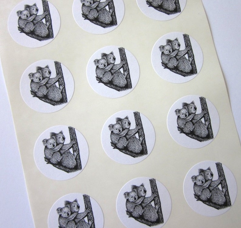 May include: Sheet of 12 round stickers featuring black and white illustrations of two koalas cuddling on a tree branch.