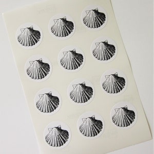 May include: Sheet of white paper with 12 black and white scallop shell stickers.