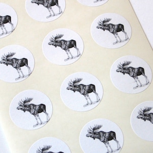 May include: Sheet of 12 round white stickers with black and white illustrations of moose. Each sticker features a different pose of a moose.