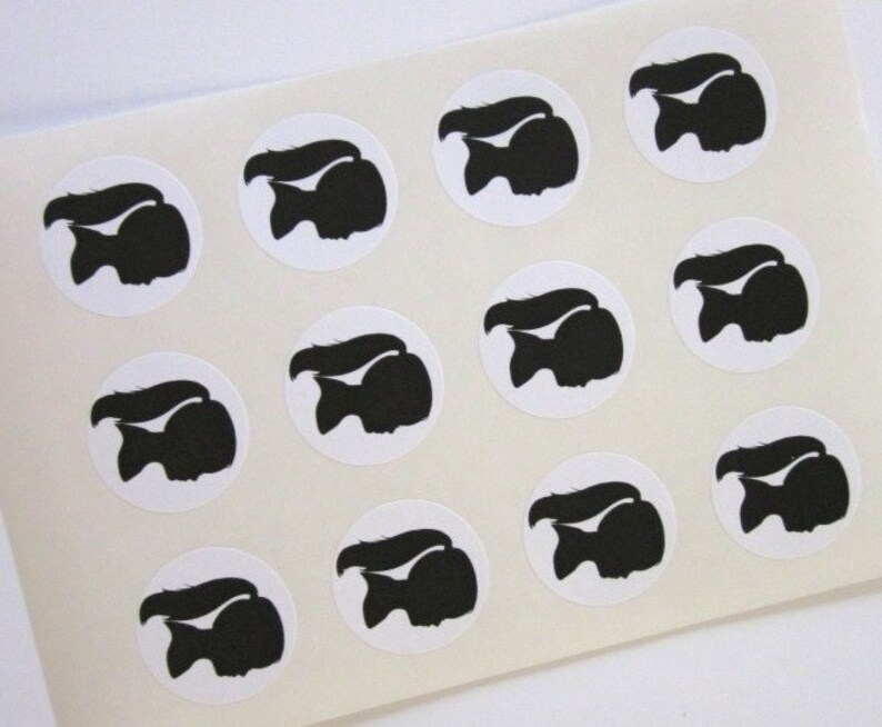 May include: Sheet of 12 white round stickers with black silhouette images of a girl with a ponytail. The girl is facing to the right.