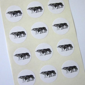 May include: Sheet of 12 round white stickers with black and white illustrations of wolves. Each sticker features a wolf with its head turned to the side, looking to the left.