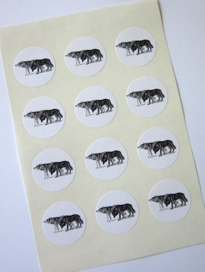May include: Sheet of 12 round white stickers with black and white illustrations of wolves. Each sticker features a wolf with its head turned to the side, looking to the left.