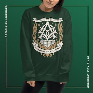 May include: Dark green sweatshirt with a white and gold emblem. The emblem reads "FOLLOW THE STARS" and "ACADEMY OF VILLAINS", with a stylized "A" and laurel branches. Officially licensed apparel.