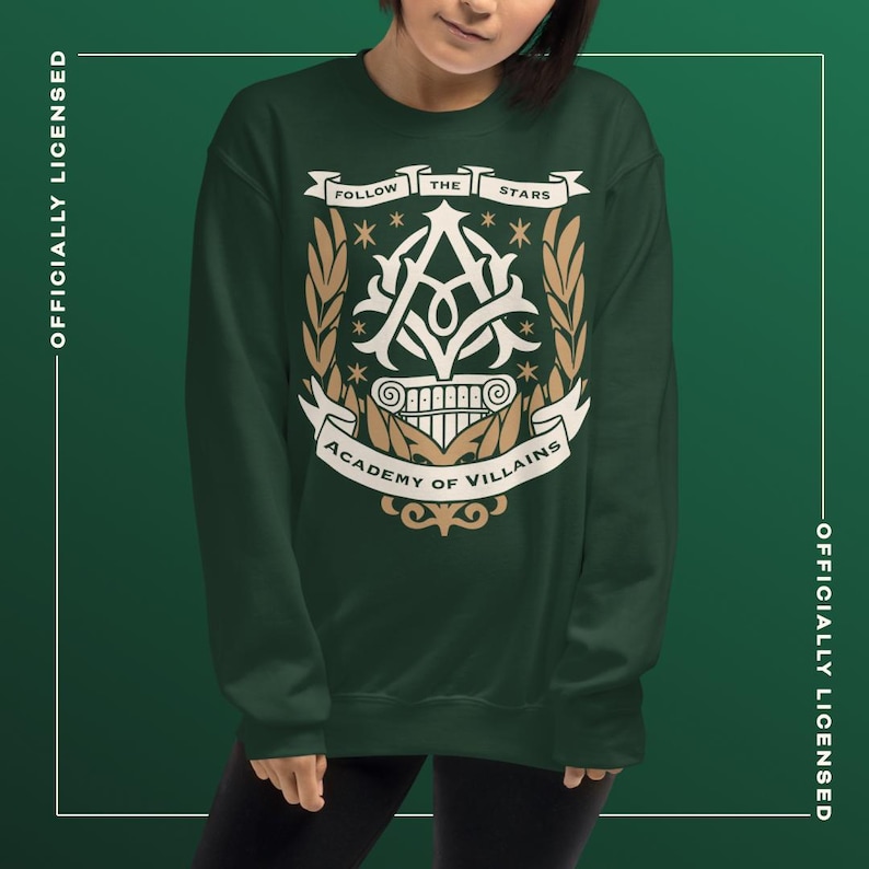 May include: Dark green sweatshirt with a white and gold emblem. The emblem reads "FOLLOW THE STARS" and "ACADEMY OF VILLAINS", with a stylized "A" and laurel branches. Officially licensed apparel.