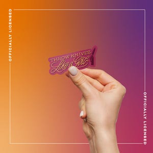 May include: A pink sticker with the text "THROW KNIVES Like a Girl" in a cursive font, held between fingers against a gradient orange and purple background. The sticker features a knife graphic. The words "OFFICIALLY LICENSED" are printed vertically on the left and right sides.