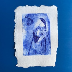 Peut inclure: Une estampe bleue et blanche d'une personne avec les mains qui lui couvrent les yeux. L'estampe est sur un fond de papier blanc.