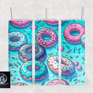May include: Three stainless steel tumblers with a blue background and a pattern of colorful donuts. The donuts are pink, blue, and green with white sprinkles.