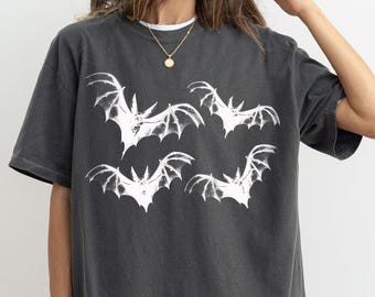 May include: A dark gray oversized t-shirt with a white graphic print of five bats flying in different directions.