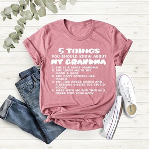 May include: A pink t-shirt with a white graphic that says "5 Things You Should Know About My Grandma" and lists five humorous facts about grandmothers.