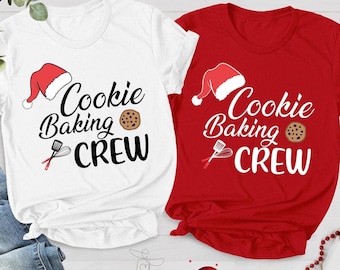 May include: Two short-sleeved t-shirts, one white and one red, with the text "Cookie Baking Crew". Each shirt features a Santa hat, a cookie, and a spatula graphic. The shirts are perfect for holiday baking.