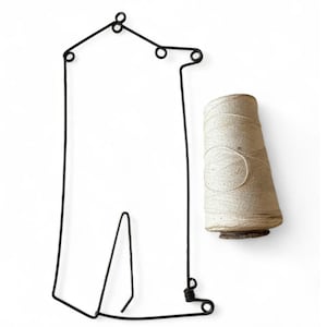 May include: A black wire frame in the shape of a house with a spool of beige twine hanging from the bottom.