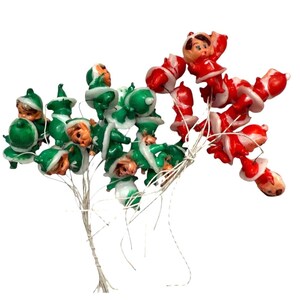 May include: Vintage Christmas light strand featuring green elf and red Santa Claus figures. The figures are made of plastic and have painted details. The lights are strung on a white wire and are designed for holiday decorating.