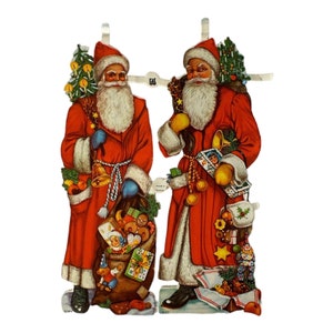 May include: Two red-suited Santa Clauses stand side-by-side, each holding a sack of gifts and a Christmas tree. They are both wearing white beards and hats, and have a jolly expression on their faces.