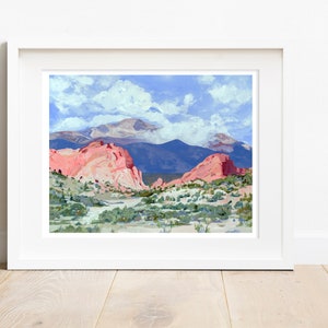 Op de afbeelding: Een schilderij van een berglandschap met rode rotsformaties op de voorgrond en een besneeuwde bergtop op de achtergrond. De lucht is blauw met witte wolken.