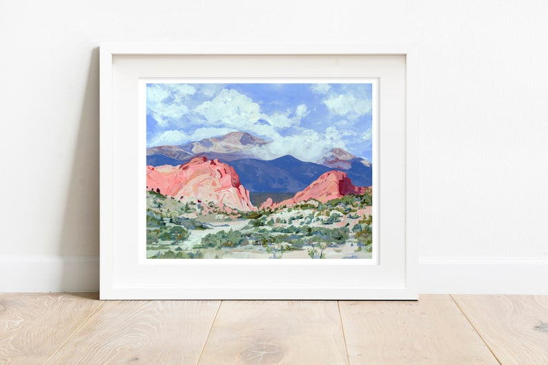 Op de afbeelding: Een schilderij van een berglandschap met rode rotsformaties op de voorgrond en een besneeuwde bergtop op de achtergrond. De lucht is blauw met witte wolken.