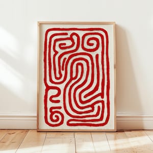 May include: Abstract art print featuring a red, maze-like design on an off-white background, framed in a natural wood. The artwork is displayed against a white wall and wooden floor, creating a minimalist aesthetic.
