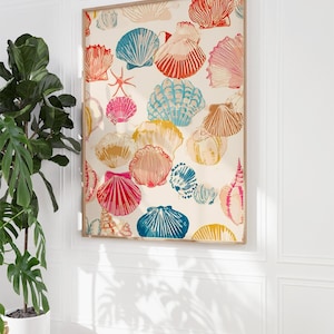 May include: A framed print featuring a repeating pattern of colorful seashells in shades of red, blue, pink, and yellow on a cream background. The artwork is displayed on a white wall, adding a coastal theme to the decor.