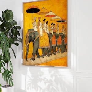 Op de afbeelding: Een ingelijste prent toont een processie van olifanten met figuren onder versierde parasols. Het kunstwerk heeft een warme gele achtergrond met gedetailleerde figuren in traditionele kledij. De olifanten zijn versierd met sierlijke bekledingen.