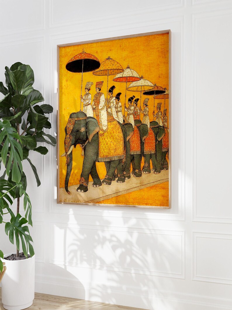 Op de afbeelding: Een ingelijste prent toont een processie van olifanten met figuren onder versierde parasols. Het kunstwerk heeft een warme gele achtergrond met gedetailleerde figuren in traditionele kledij. De olifanten zijn versierd met sierlijke bekledingen.