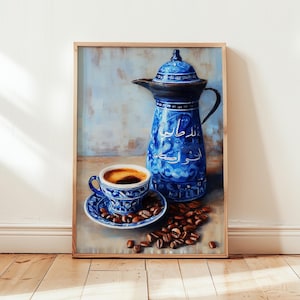 May include: A framed painting shows a blue coffee pot and cup with a saucer, filled with coffee and surrounded by coffee beans. The pot and cup have intricate patterns and Arabic script. The artwork is set against a light blue and beige background.