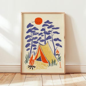 Puede incluir: Una impresión enmarcada que presenta una escena de acampada. La obra de arte representa una tienda de campaña amarilla y naranja, un sol rojo, árboles azules y dos hogueras. El estilo recuerda a una xilografía, con una estética minimalista.