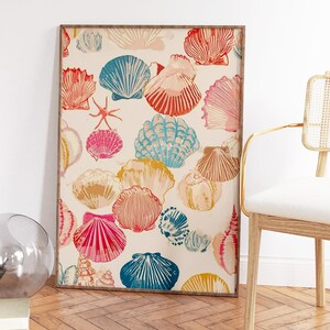 May include: A framed print featuring a pattern of colorful seashells in shades of red, pink, blue, and yellow on a cream background. The artwork is displayed in a room with a wooden floor and a chair.