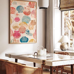 May include: A framed art print featuring a colorful seashell pattern in shades of pink, blue, orange, and yellow. The artwork is displayed in a light-filled room with a dining table and chairs.