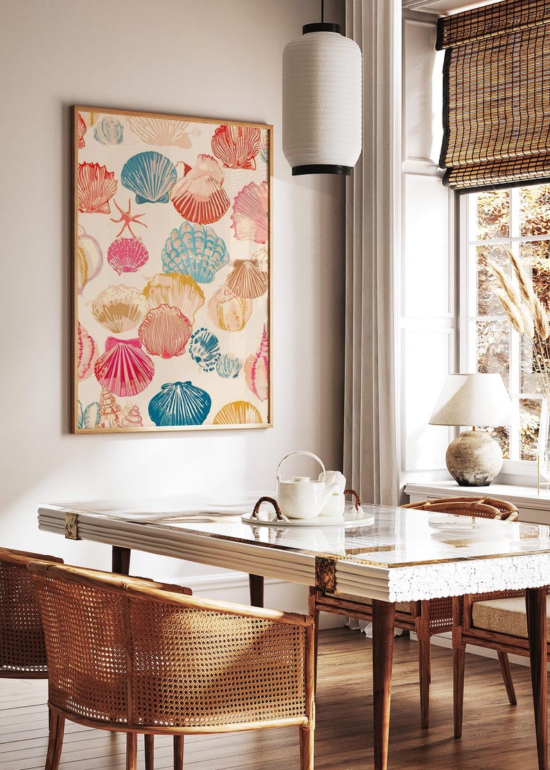 May include: A framed art print featuring a colorful seashell pattern in shades of pink, blue, orange, and yellow. The artwork is displayed in a light-filled room with a dining table and chairs.