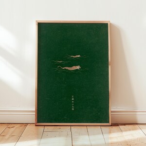 May include: Framed art print depicting two tigers swimming in a dark green sea. The tigers have orange and black stripes. The artwork is in a wooden frame and has Japanese text at the bottom.