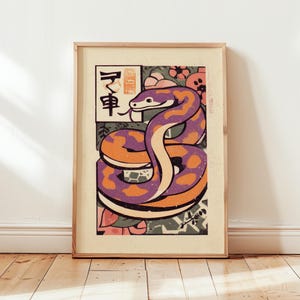 Puede incluir: Impresión artística enmarcada con una ilustración estilizada de una serpiente. La serpiente está representada en tonos morados y naranjas con un diseño estampado. El fondo incluye elementos florales y geométricos, con texto japonés.