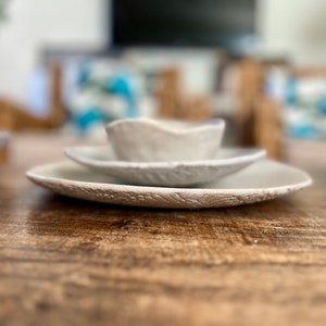 May include: A set of three white ceramic bowls with a textured surface. The bowls are stacked on top of each other, with the smallest bowl on top.