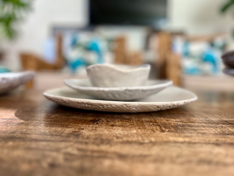 May include: A set of three white ceramic bowls with a textured surface. The bowls are stacked on top of each other, with the smallest bowl on top.