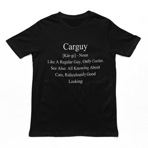 May include: Black t-shirt with white text that reads "Carguy [Kär-gi] - Noun Like A Regular Guy, Only Cooler. See Also: All Knowing About Cars, Ridiculously Good Looking"