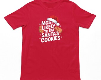 May include: A red t-shirt with the text "MOST LIKELY TO EAT SANTA'S COOKIES" in white, with a Santa hat and cookie graphics. The shirt is a short-sleeved crew neck.