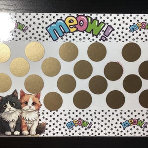 May include: A white card with a black and white paw print pattern. The card has gold circles on it and the word "meow!" in colorful letters. There are two cartoon cats on the bottom of the card, one black and one orange.