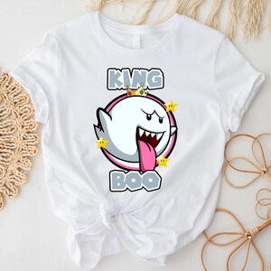 Op de afbeelding: Wit T-shirt met een afbeelding van King Boo uit de Super Mario-franchise. De afbeelding toont King Boo met een kroon en omringd door sterren. De tekst "KING BOO" is gedrukt in grijze letters.