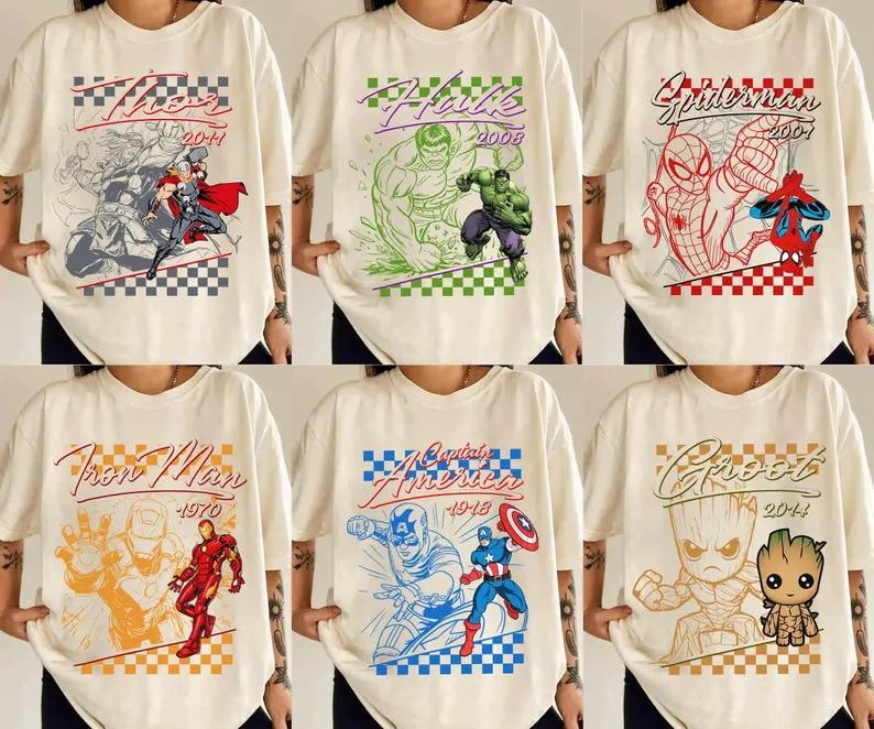 Puede incluir: Camisetas color crema con varios personajes de Marvel. Los dise&ntilde;os incluyen a Thor, Hulk, Spider-Man, Iron Man, Capit&aacute;n Am&eacute;rica y Groot, cada uno con un gr&aacute;fico y un a&ntilde;o &uacute;nicos. Las camisetas tienen un patr&oacute;n de cuadros en la parte superior e inferior.
