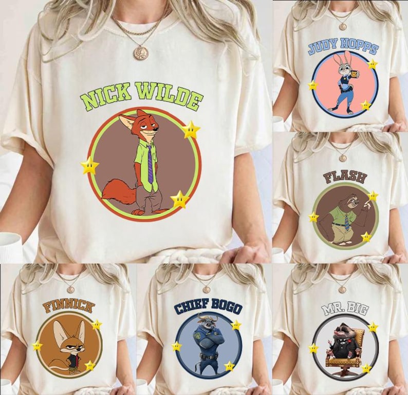 May include: Cream-colored t-shirts featuring cartoon characters from the movie Zootopia. Each shirt displays a character's name in a circle with a corresponding image and star accents. Characters include Nick Wilde, Judy Hopps, Flash, Finnick, Chief Bogo, and Mr. Big.