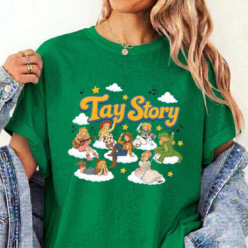 Pu&ograve; includere: Una t-shirt verde con il testo giallo Tay Story sopra un'illustrazione grafica di diversi personaggi dei cartoni animati con vari abiti, tutti posizionati su nuvole bianche circondate da stelle gialle e piccole note musicali nere.