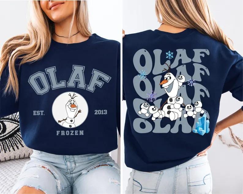 May include: Navy blue sweatshirt featuring the word "OLAF" in a collegiate font. The front design includes a circular graphic of Olaf the snowman from Frozen, with "EST. 2013" and "FROZEN" below. The back has a repeating "OLAF" design with Olaf and snowgies.