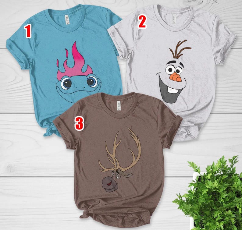 Pu&ograve; includere: Tre magliette a maniche corte con disegni di personaggi dei cartoni animati. Una &egrave; azzurra con un lucertola dei cartoni animati, un'altra &egrave; bianca con la faccia di Olaf e la terza &egrave; marrone con una renna dei cartoni animati.