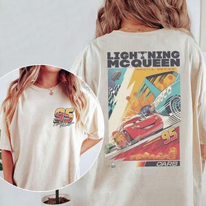 May include: Cream-colored t-shirt featuring Lightning McQueen racing graphics. The front displays a "95" logo, while the back showcases a vibrant racing scene with the text "Lightning McQueen Racing Series" and "Cars".