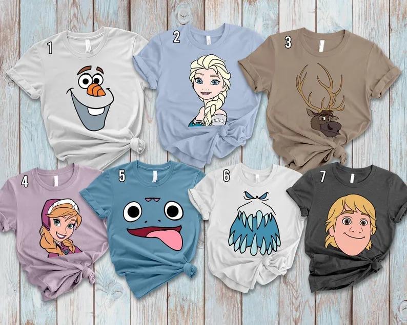 May include: Seven short-sleeved t-shirts with cartoon character designs. The shirts are various colors, including white, light blue, brown, purple, and charcoal. Each shirt features a different character face from a popular animated movie.