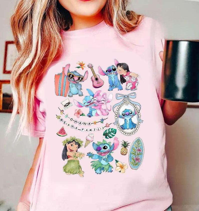 Może przedstawiać: Jasnor&oacute;żowy t-shirt z kolorowym nadrukiem graficznym przedstawiającym postać Stitcha i Lilo. Wz&oacute;r zawiera r&oacute;żne ilustracje, takie jak deska surfingowa, ukulele, tropikalne kwiaty, ananas oraz napis O-H-A-N-A M-E-A-N-S F-A-M-I-L-Y.