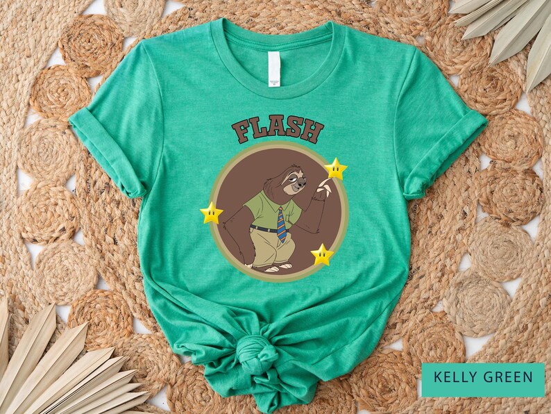 May include: Kelly green t-shirt featuring a cartoon sloth character wearing a green shirt and tie, with the word "FLASH" above the sloth. The sloth is inside a brown circle with three yellow stars.