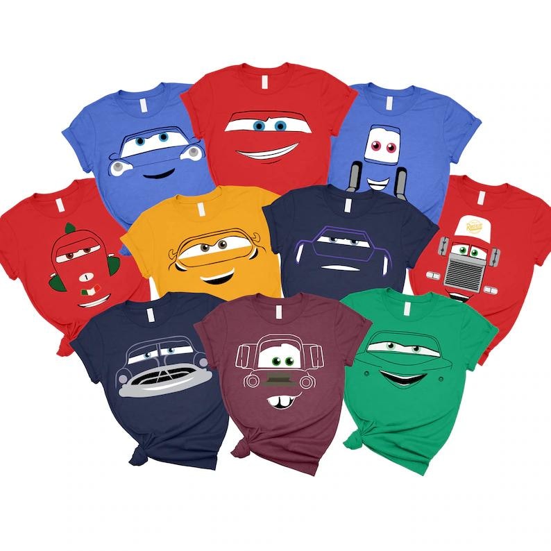 May include: A collection of ten colorful t-shirts featuring cartoon car designs. The shirts are in various colors, including red, blue, green, and yellow. Each shirt has a different car face design, with smiling faces and headlights.