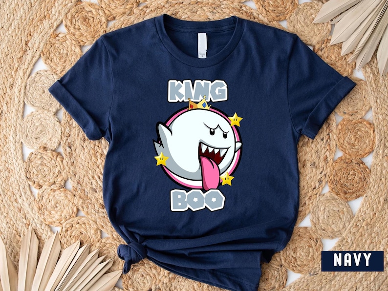 Op de afbeelding: Een marineblauw t-shirt met een afbeelding van King Boo uit de Super Mario-franchise. De afbeelding toont King Boo met een kroon en omringd door sterren. De tekst "King Boo" is onder de afbeelding gedrukt.