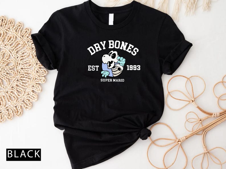 May include: Black t-shirt with a white graphic of a skeleton wearing a blue cap and holding a bone. The graphic says "Dry Bones Est 1993 Super Mario".